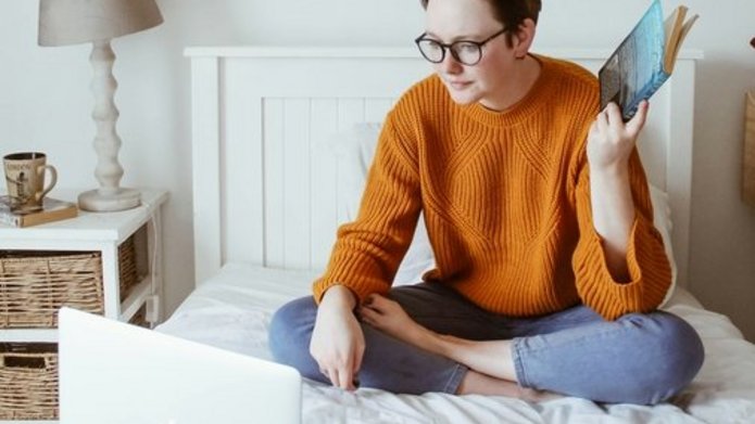 Osoba ucząca się na łóżku przed komputerem